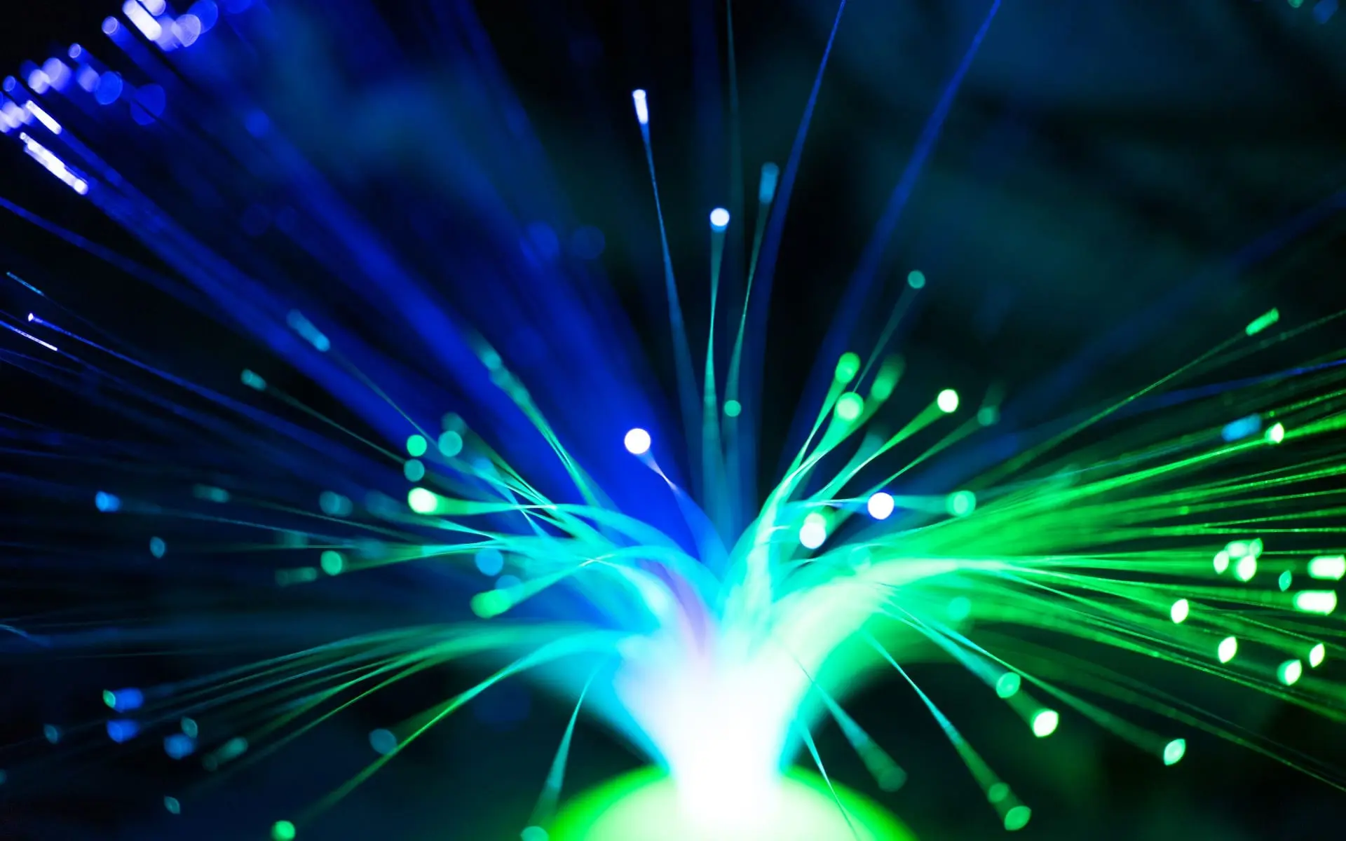 Lámpara de fibra óptica con haces de luz azul y verde sobre un fondo oscuro