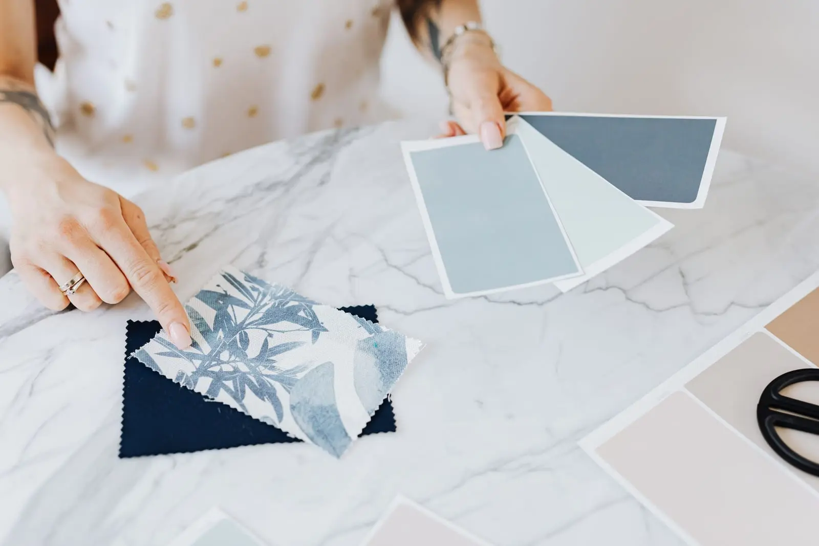 Manos eligiendo muestras de color y textura sobre una mesa de mármol para un diseño